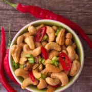 overhead shot of a bowl of cashews with slices of red chilli