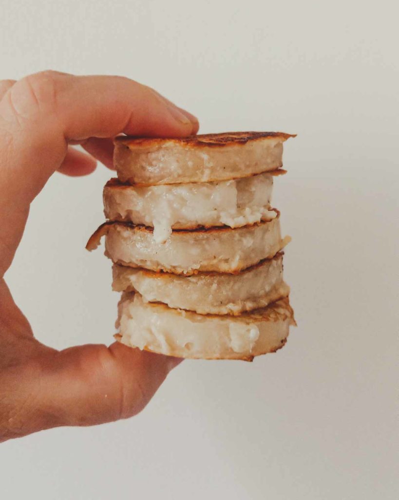 hand holding a stack of kanom baa bin which have been fried in a ring, hence a uniform shape