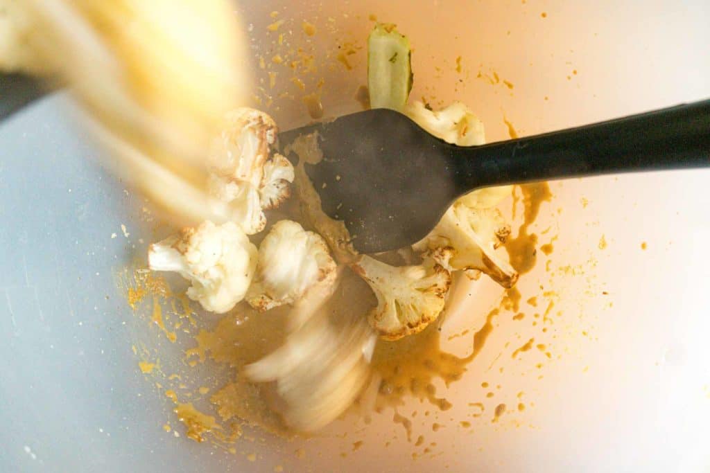adding roasted cauliflower to a bowl with nutritional yeast and Chinkiang vinegar