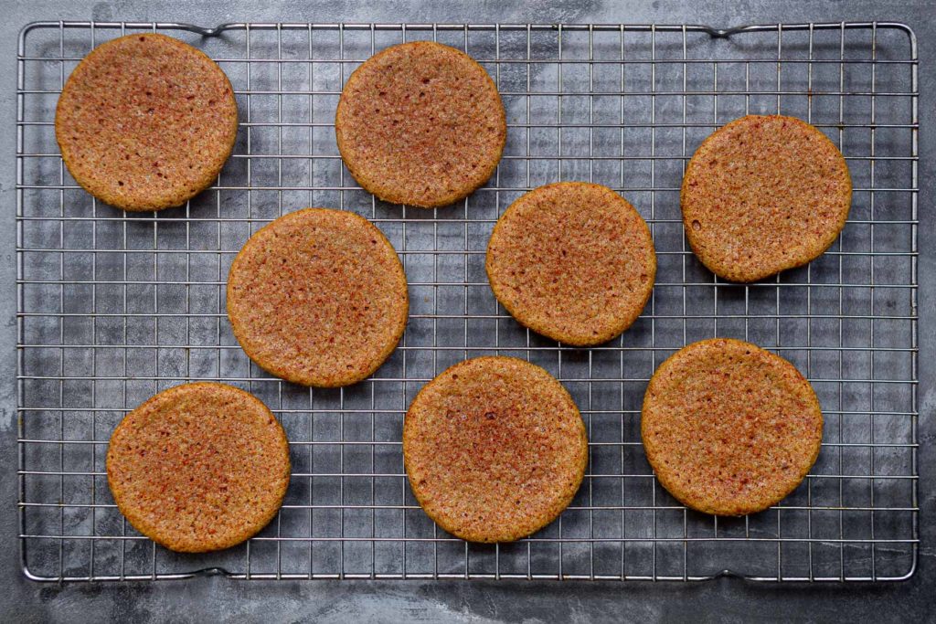 8 turmeric cookies on a cooling rack, with a dark grey background