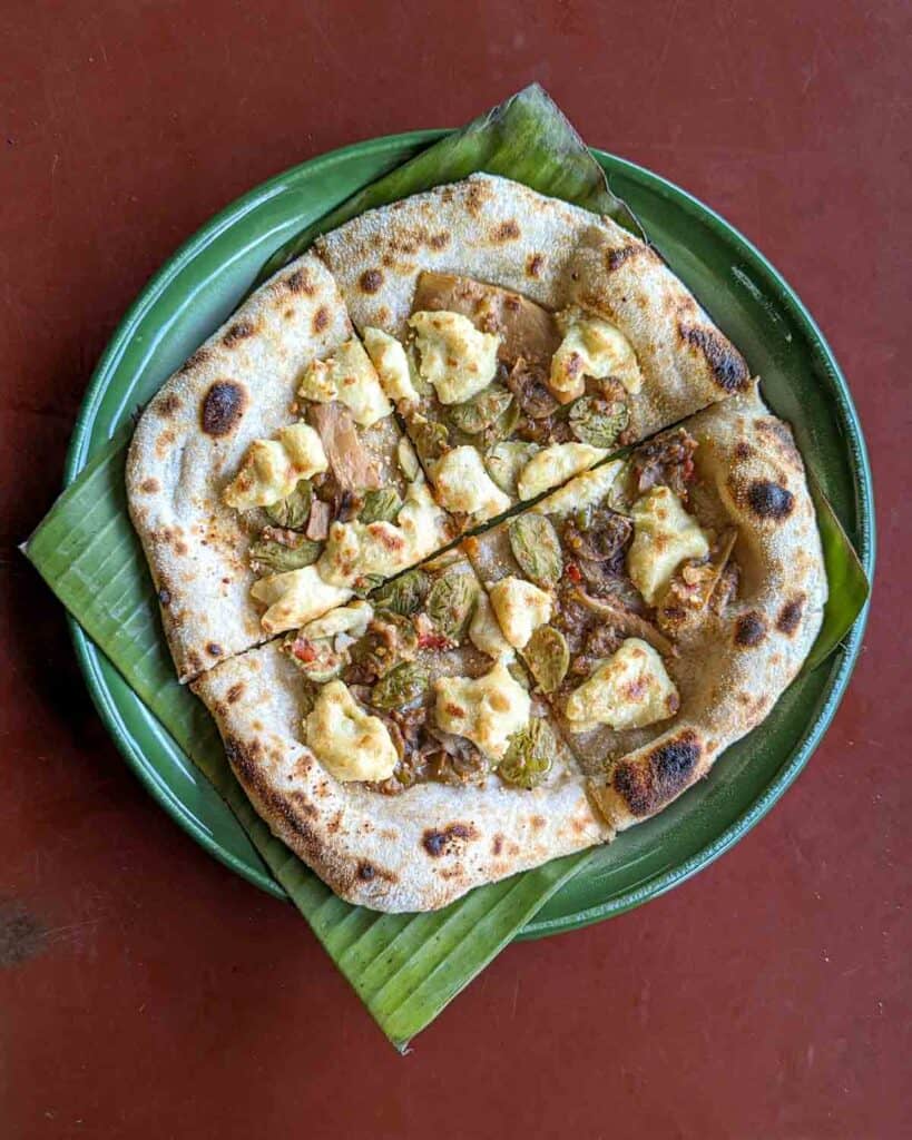 Overhead shot of a pizza with vegan shrimp paste, stink beans, and vegan cheese