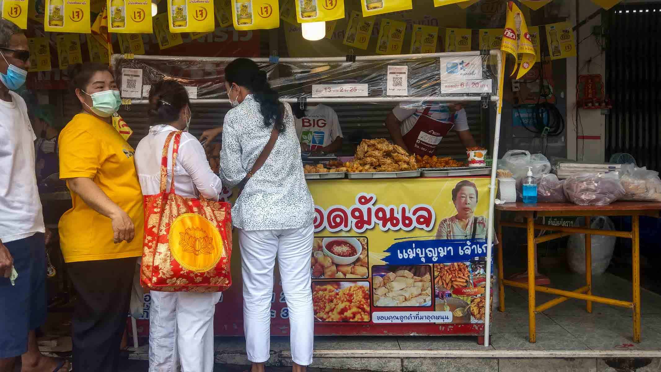 Stall selling deep fried corn cakes, tofu, and other items, with people queuing.