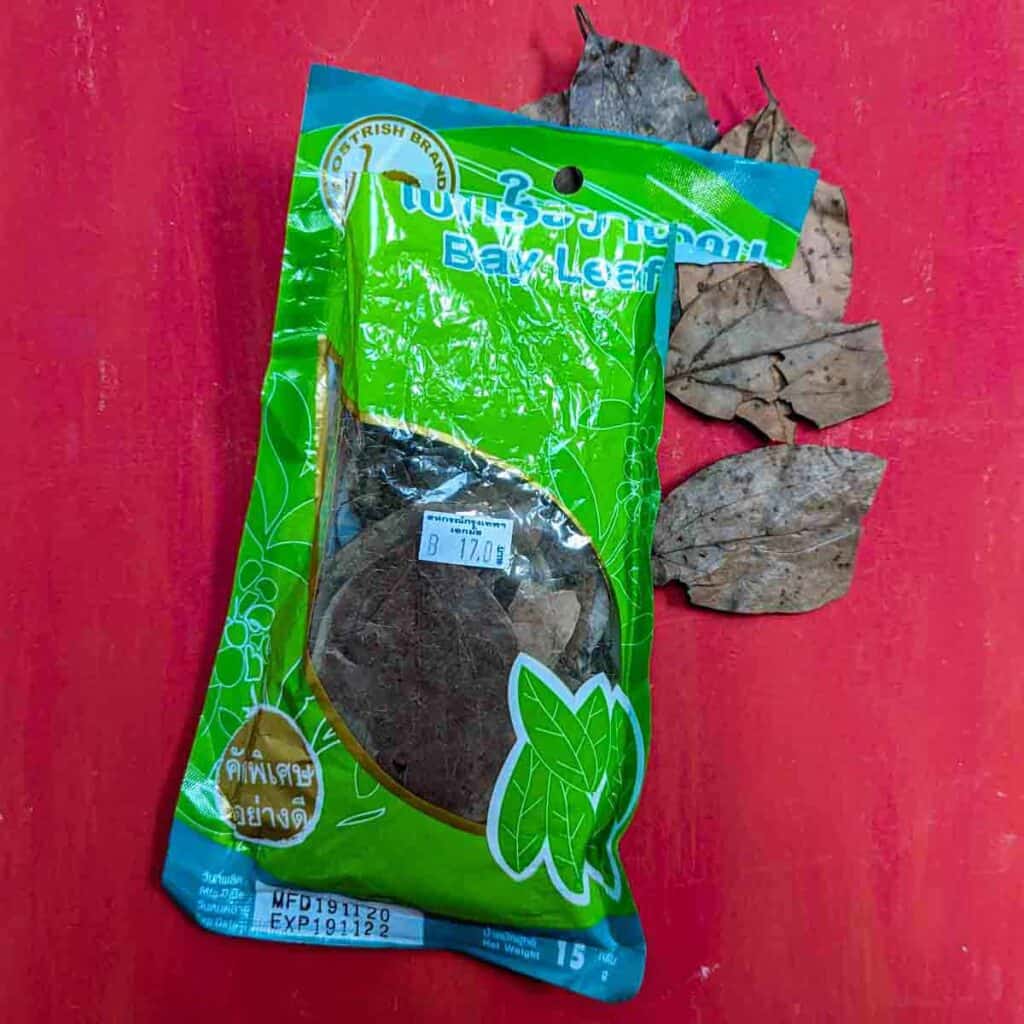 Bag of opened Thai bay leaves on a red background